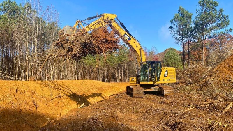 Komatsu excavator trenching during a land clearing project